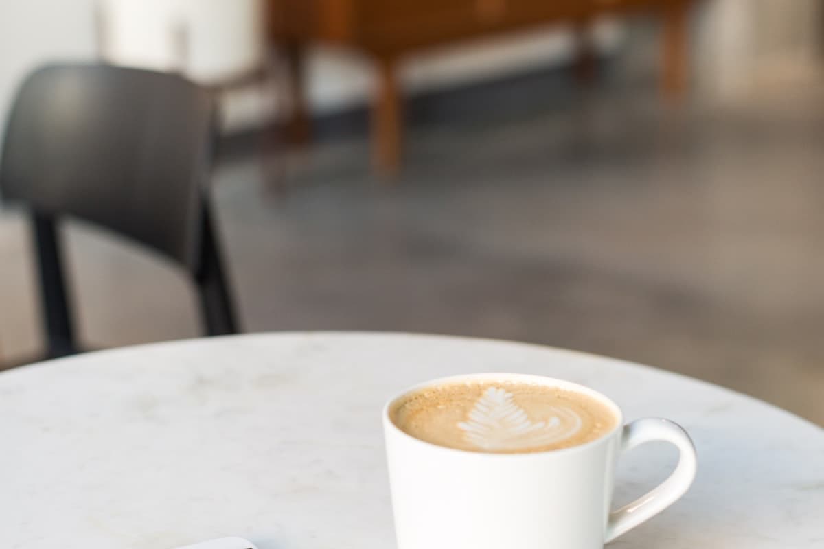 A coffee on a cafe table next to a phone showing a rating prompt